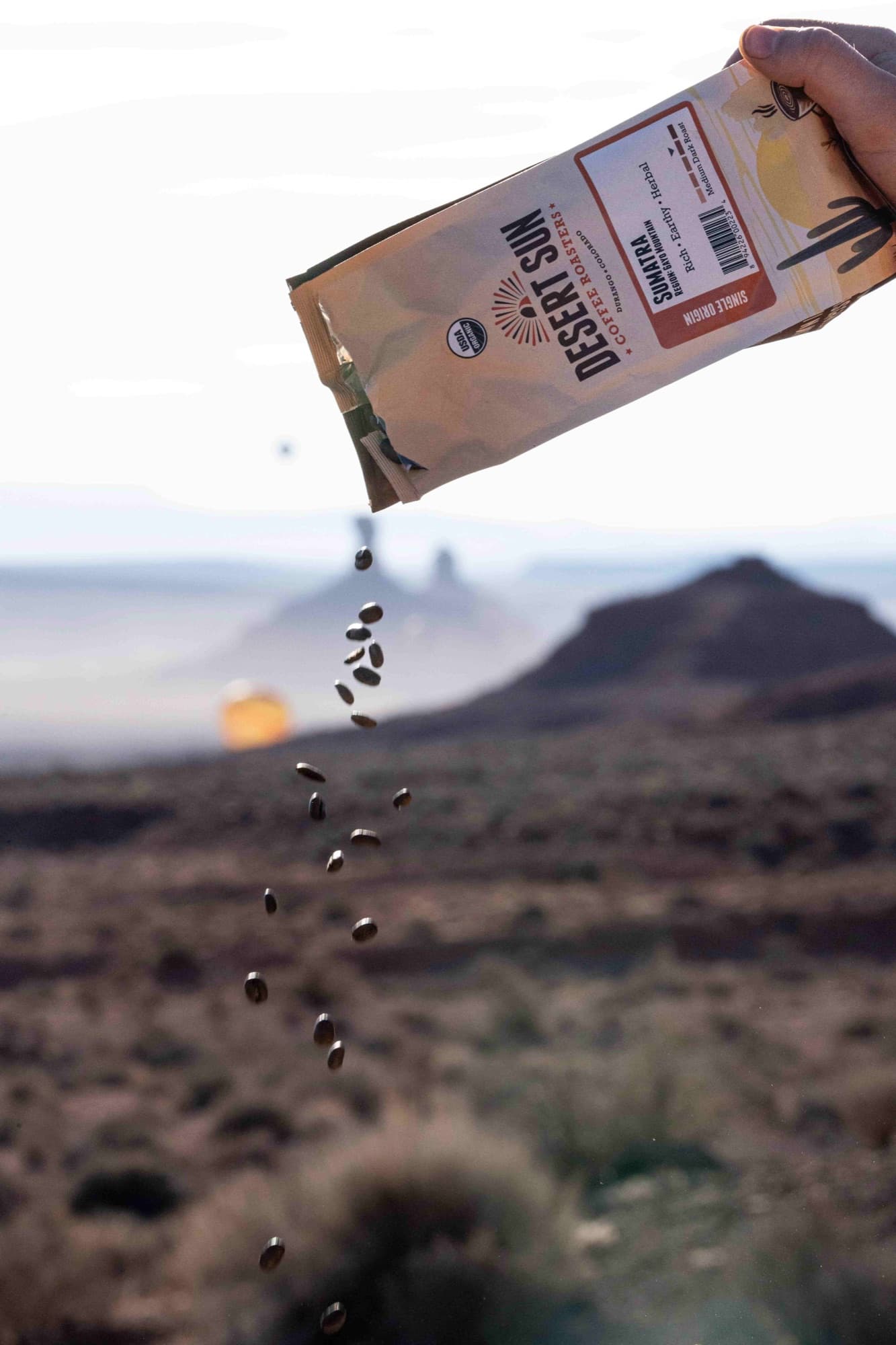 Coffee beans pour from a Desert Sun bag against a desert horizon