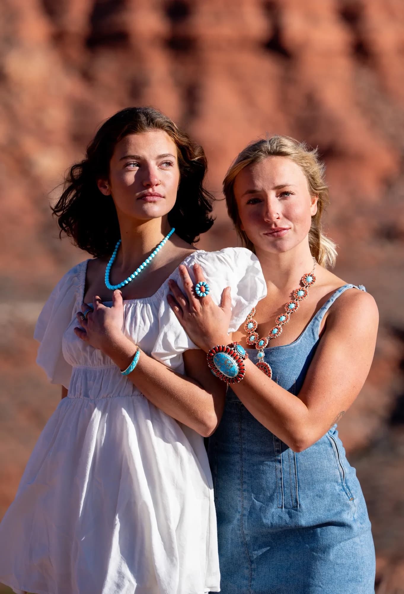Two models in white and denim wearing turquoise jewelry against red rock