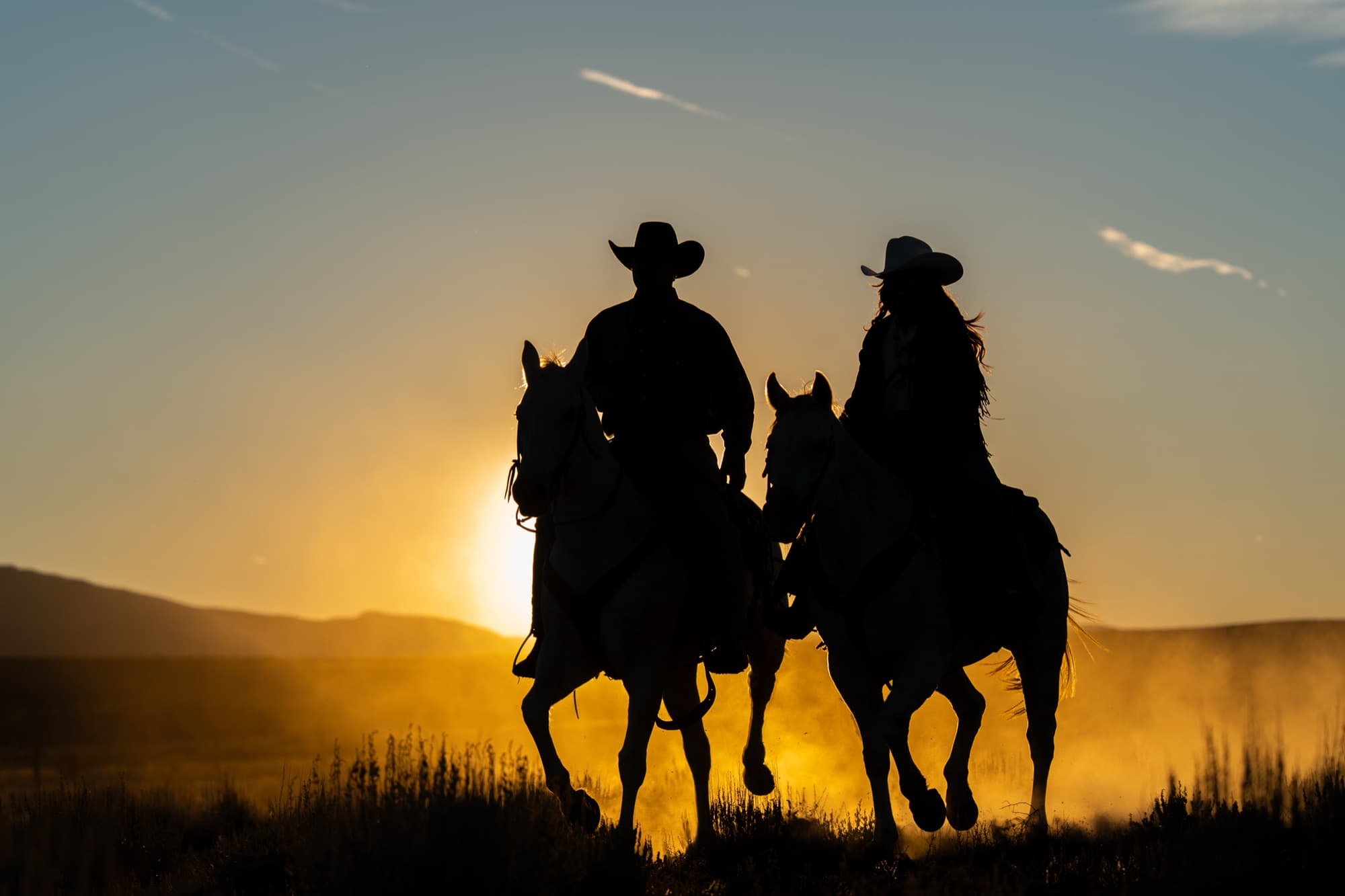 Two riders silhouetted against a desert sunset